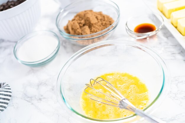 Mixing ingredients in a glass mixing bowl to bake chocolate chip cookies.