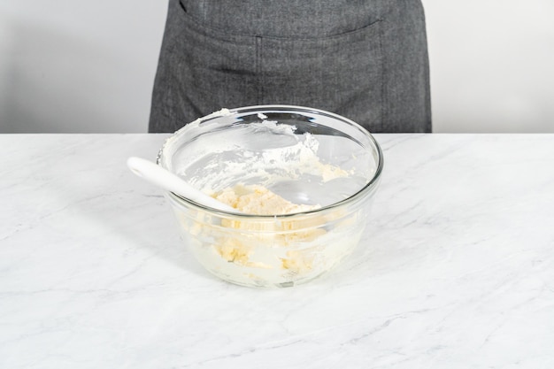 Mixing ingredients in a glass mixing bowl to bake mascarpone tart with fresh berries.