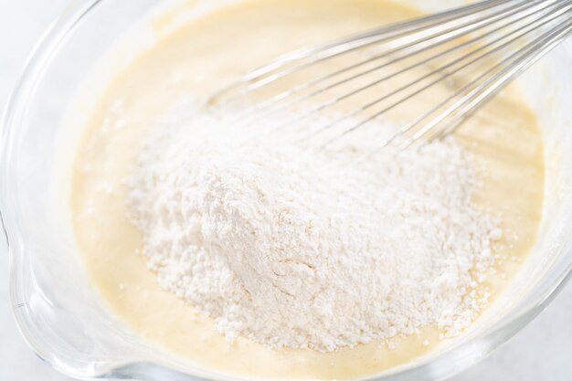 Mixing ingredients in a glass mixing bowl to prepare coconut banana pancakes