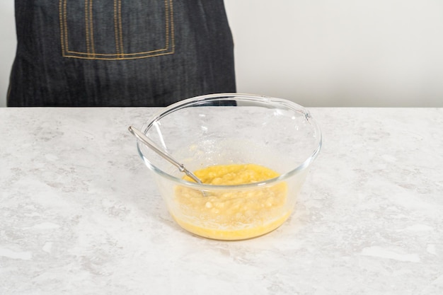 Mixing ingredients in a glass mixing bowl to prepare coconut banana pancakes