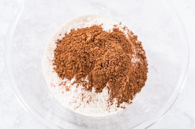 Mixing ingredients in a glass mixing bowl to prepare red velvet bundt cake.