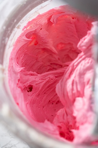 Mixing ingredients in kitchen electric mixer to make ombre pink buttercream frosting