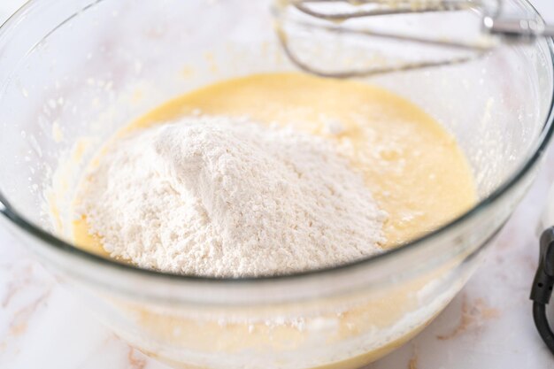 Mixing ingredients in a large glass mixing bowl to bake apple bundt cake with caramel glaze.