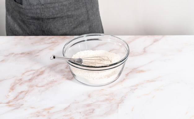 Mixing ingredients in a large glass mixing bowl to bake apple bundt cake with caramel glaze.