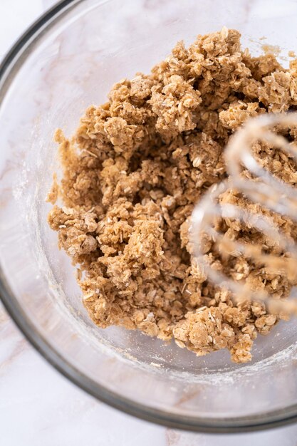 Mixing ingredients in a large glass mixing bowl to bake apple oatmeal cookies