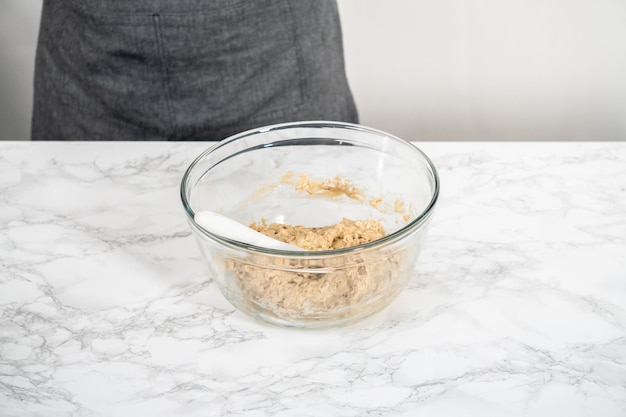 Mixing ingredients in a large glass mixing bowl to bake banana oatmeal muffins