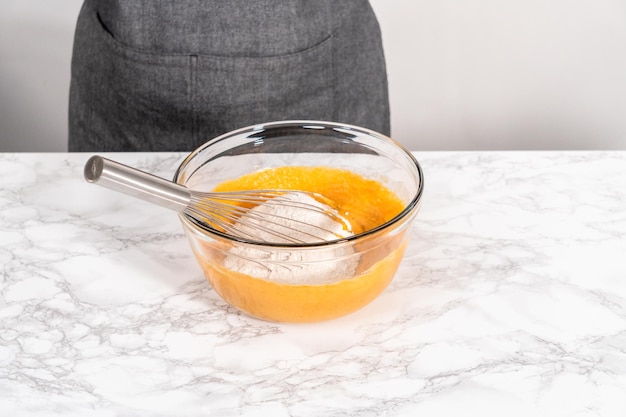 Mixing ingredients in a large glass mixing bowl to bake chocolate pumpkin bundt cake with toffee glaze