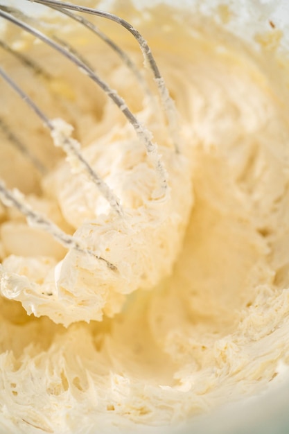 Mixing ingredients in a large glass mixing bowl of kitchen mixer to make eggnog buttercream frosting