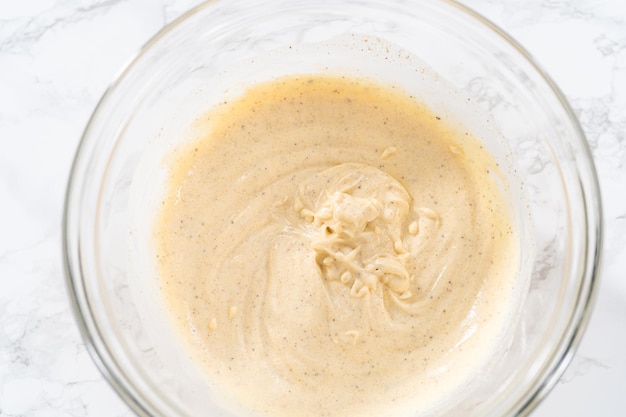 Mixing ingredients in a large glass mixing bowl to make dressing for macaroni salad with chicken