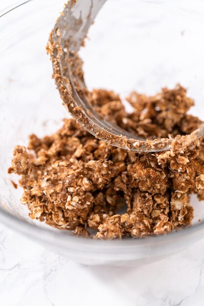 Mixing ingredients in a large glass mixing bowl to prepare cinnamon crumb topping.