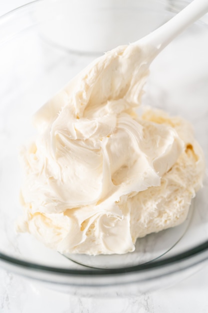 Mixing in store-bought buttercream frosting in a glass mixing bowl.