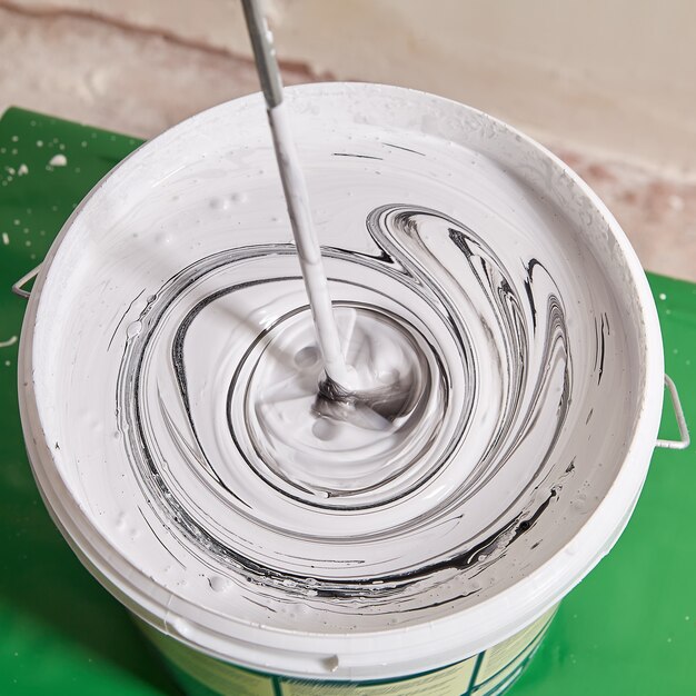 Mixing white paint with black pigment to obtain gray color.