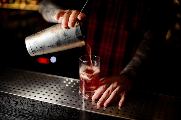 Mixologist die zoete sappige cocktail gieten in een glas op bar