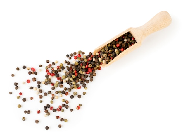 A mixture of pepper peas poured from a wooden spoon on a white