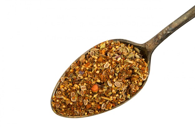 A mixture of seasonings in an old spoon on a white background. 