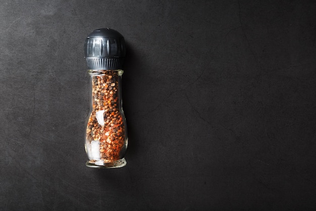 Photo a mixture of seasonings, spices and herbs in a glass mill on a black background.