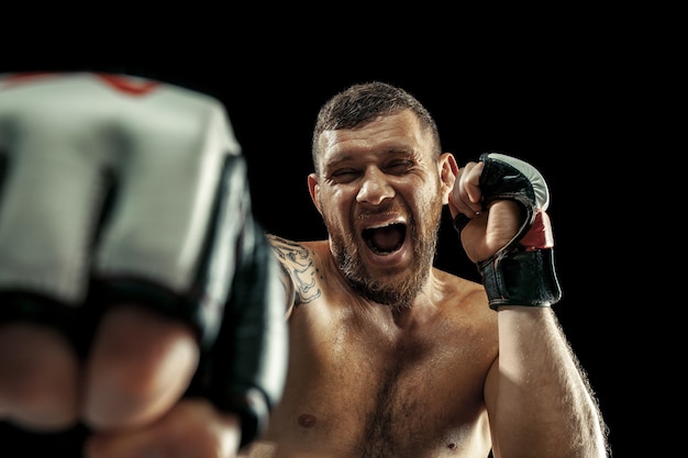 Mma. pugile professionista boxe isolato su nero di sfondo per studio. fit muscolare atleta caucasico combattendo. concetto di sport, competizione, eccitazione ed emozioni umane