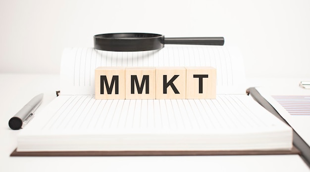 Mmkt word concept. wooden cubes, notepad, pen and business charts.