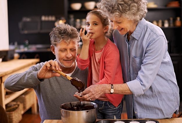 照片mmmthis好肖像的一个小女孩和她的祖父母在厨房里做蛋糕