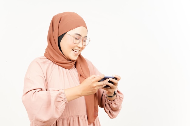 Mobiel spel spelen op smartphone van mooie Aziatische vrouw die hijab draagt die op wit wordt geïsoleerd