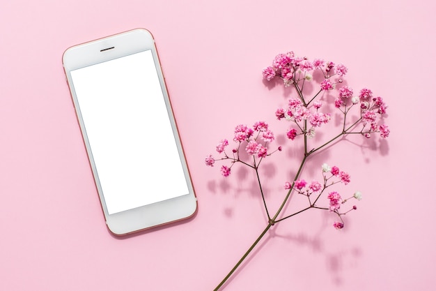 Mobiele telefoon en roze bloemen op roze pasteltafel