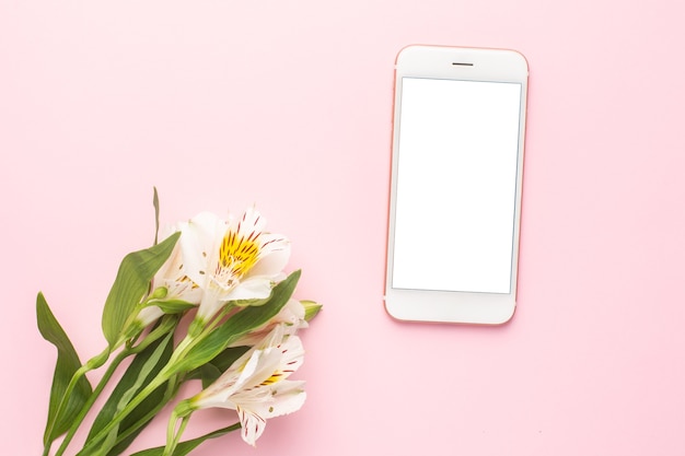 Mobiele telefoon en witte bloem Alstroemeria op roze