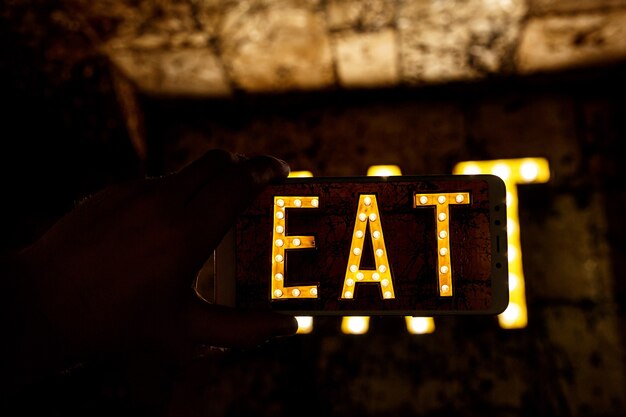 Mobiele telefoon fotografie. Afbeelding van woord eten geschreven door gloeilampen.