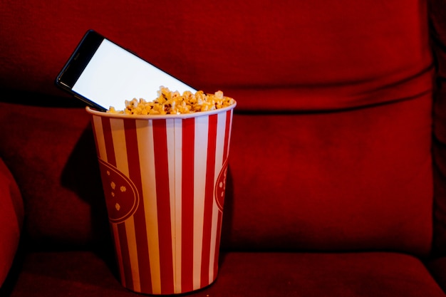 Mobiele telefoon met lege witte helder scherm in popcorn emmer