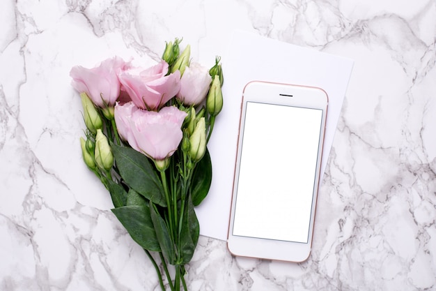 Mobiele telefoon met roze bloemen op marmer