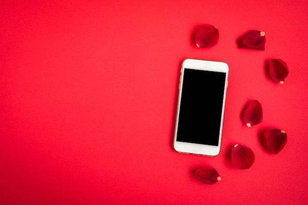 Mobiele telefoon met rozenblaadjes op rood.