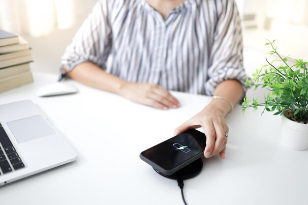 Mobiele telefoon opladen met draadloos oplaadapparaat in de tafel Smartphone opladen op een oplaadpad