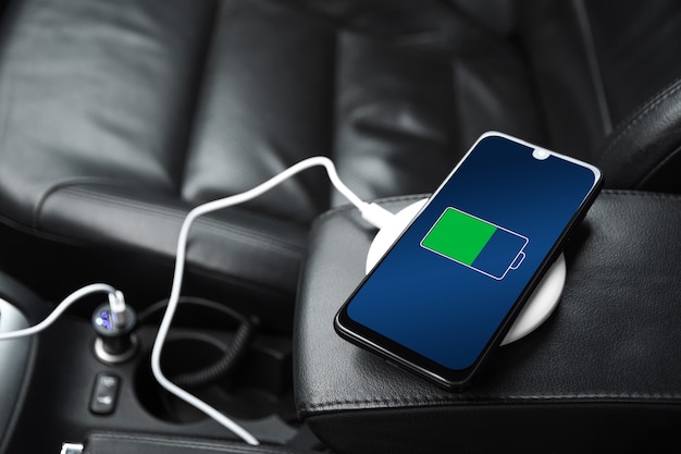 Mobiele telefoon, smartphone, mobiele telefoon is opgeladen, laad de batterij op met USB-oplader in de binnenkant van de auto. modern zwart auto-interieur