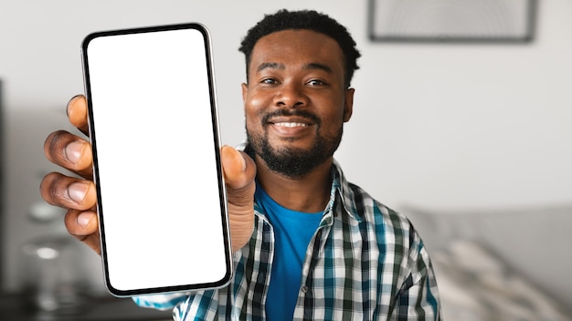 白い画面で大きな空白のスマート フォンを示すモバイル広告幸せな黒人男性