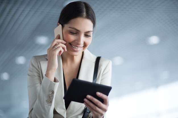 Mobile businesswoman using tablet and phone