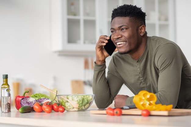 Mobile communication happy handsome black man talking on cellphone in kitchen