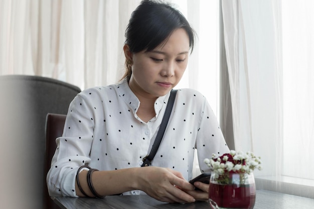 Foto stile di vita mobile la donna asiatica usa lo smartphone per chattare e lavorare nella caffetteria