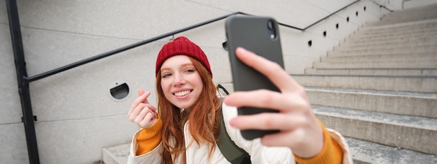 사진 ⁇ 드폰과 사람들의 라이프스타일 스타일리쉬한  ⁇ 은 머리 소녀는 스마트폰으로 셀카를 찍고 포즈를 취합니다.