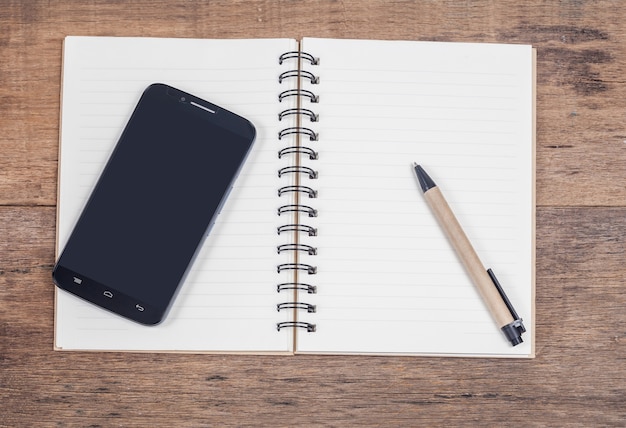 mobile phone and book note in vintage wooden desk.