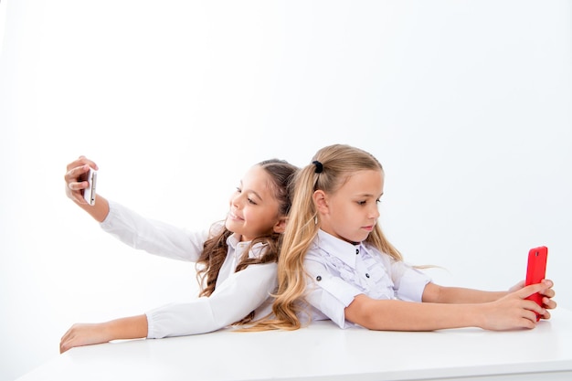 Mobile phone dependence and selfie. small kids make selfie on phone at school isolated on white, copy space. students life with mobile phone dependence.