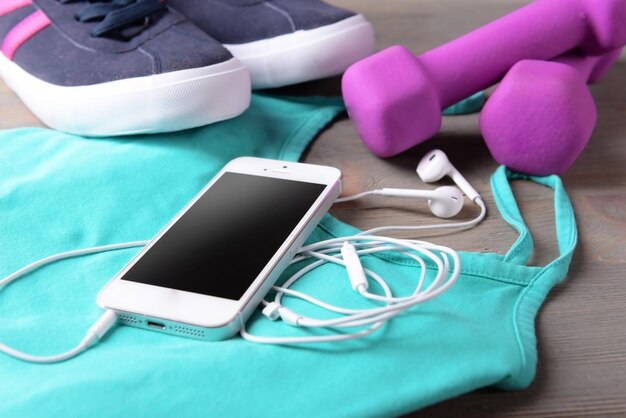 Mobile phone and earphones with set for sports on wooden table closeup