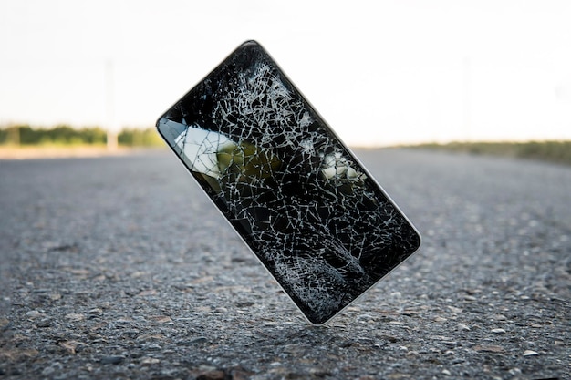 휴대전화가 아스팔트에서 추락하고 깨진 스마트폰이 땅으로 날아가는 파손된 파손된 휴대폰 사고 가제트 개념으로 장치 수리 충돌 테스트 필요