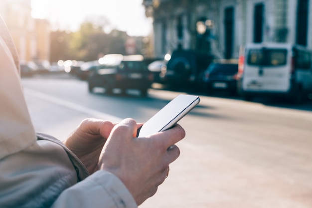 Mobile phone in female hands against city surface