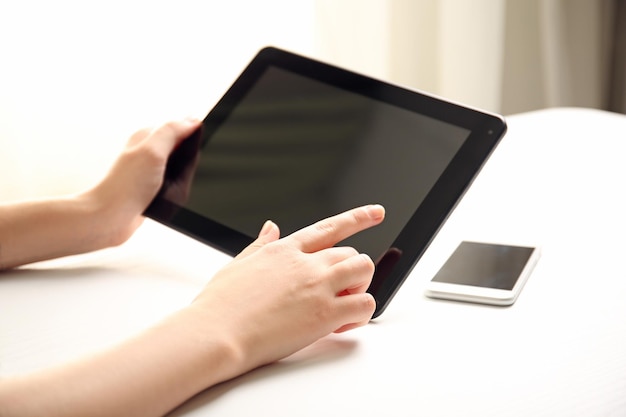 Mobile phone and female hands using modern tablet indoors