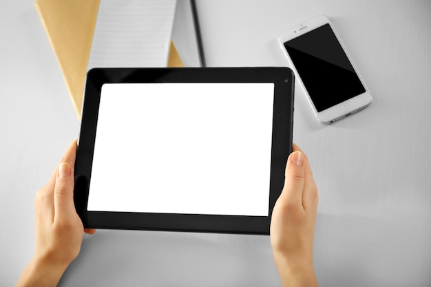 Foto telefono cellulare e mani femminili utilizzando un moderno tablet al chiuso
