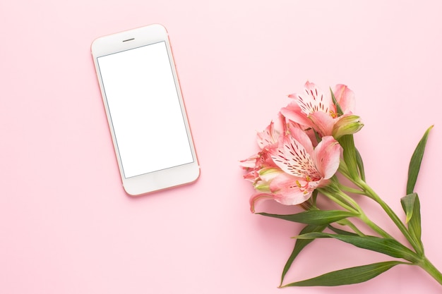 Mobile phone and flower Alstroemeria on a pink