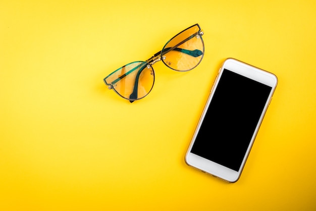 Mobile phone and glasses on yellow