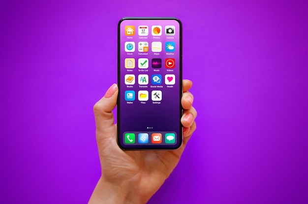 Mobile phone in hand on purple background with sample home
screen icons on the screen