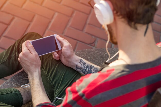 男の手の中の携帯電話。若者はスマートフォンを使います。