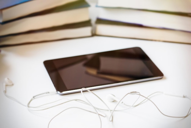 Photo mobile phone and headphones with stack of books on table