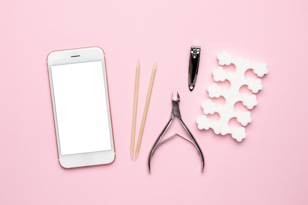 Mobile phone and manicure and pedicure tools on pink